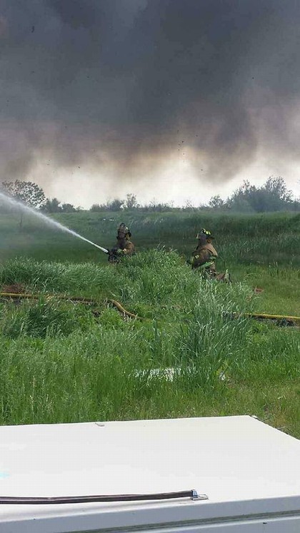 two firefighters in a field with water hose 