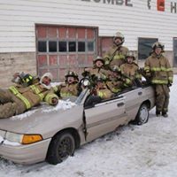 group of firefighters posing on car