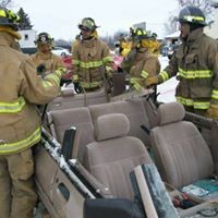 firefighters surrounding a car without a roof