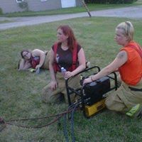 three firefighters sitting in green grass