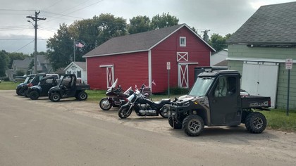 red shed with line of motorcycles and one four wheeler