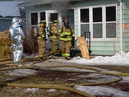 Firefighters with water hose putting out house fire
