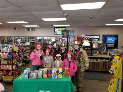 three firefighters and girl scouts in front of green table