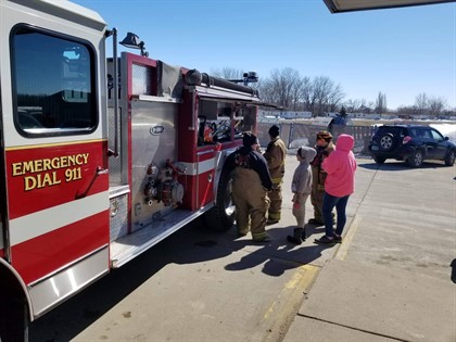 Girl Scouts going into red firetruck with firefighters