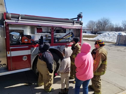 Girl scouts looking at red firetruck with firefighters
